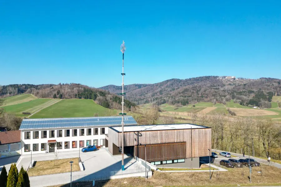 Das Dorfgemeinschaftshaus Kumreut aus der Luft mit den Hügeln des Bayerischen Waldes