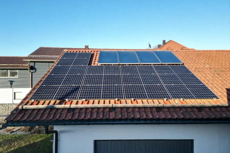 Solarkollektoren über Photovoltaikmodulen auf einem Ziegeldach in Außernbrünst
